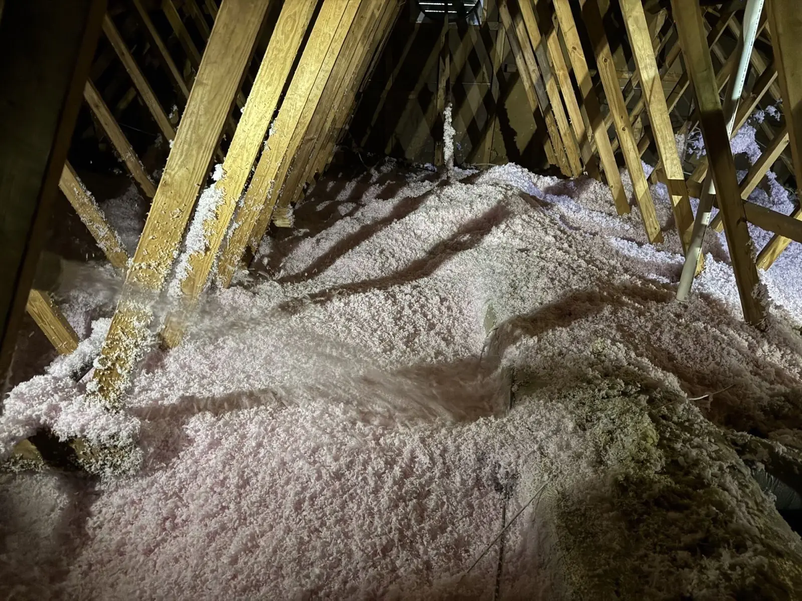 Fresh blown-in attic insulation between trusses on a Multi-Family Roofing job