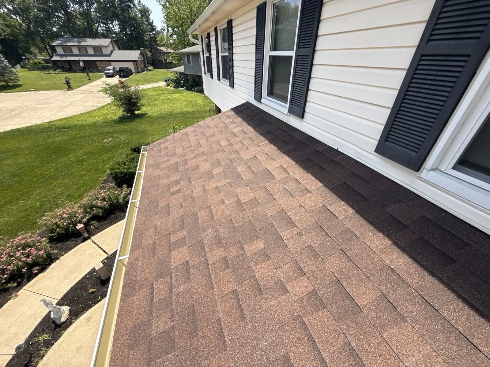 New white seamless gutters installed along a brown shingle roofline on an Indianapolis area home